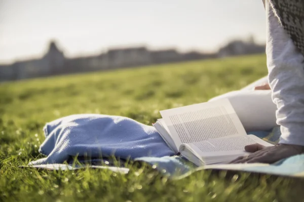 Close-up of Woman Reading Book on Blanket in Meadow Close-up of Woman Reading Book on Blanket in Meadow